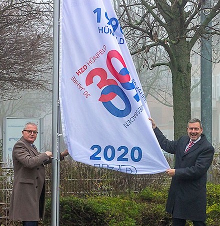 HZD-Direktor Joachim Kaiser (l.) und Technischer Direktor Thomas Kaspar hissen die Jubiläumsflagge vor der HZD-Zentrale.