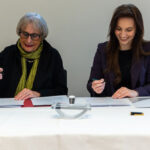 Zwei Frauen unterschreiben Verträge.