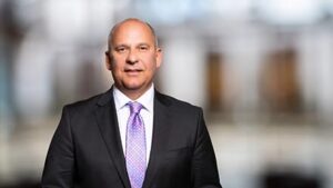 Brustbild von Roman Poseck in dunklem Anzugjackett und violettem Schlips.