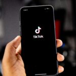 Eine Hand hält ein Smartphone hoch, auf dessen Screen das TikTok-Logo zu sehen ist.