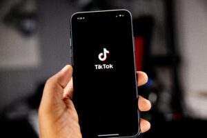 Eine Hand hält ein Smartphone hoch, auf dessen Screen das TikTok-Logo zu sehen ist.