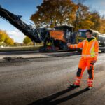 Das Bild zeigt die Baustelle einer Straßensanierung mit einem Bauarbeiter mit digitalem Gerät.