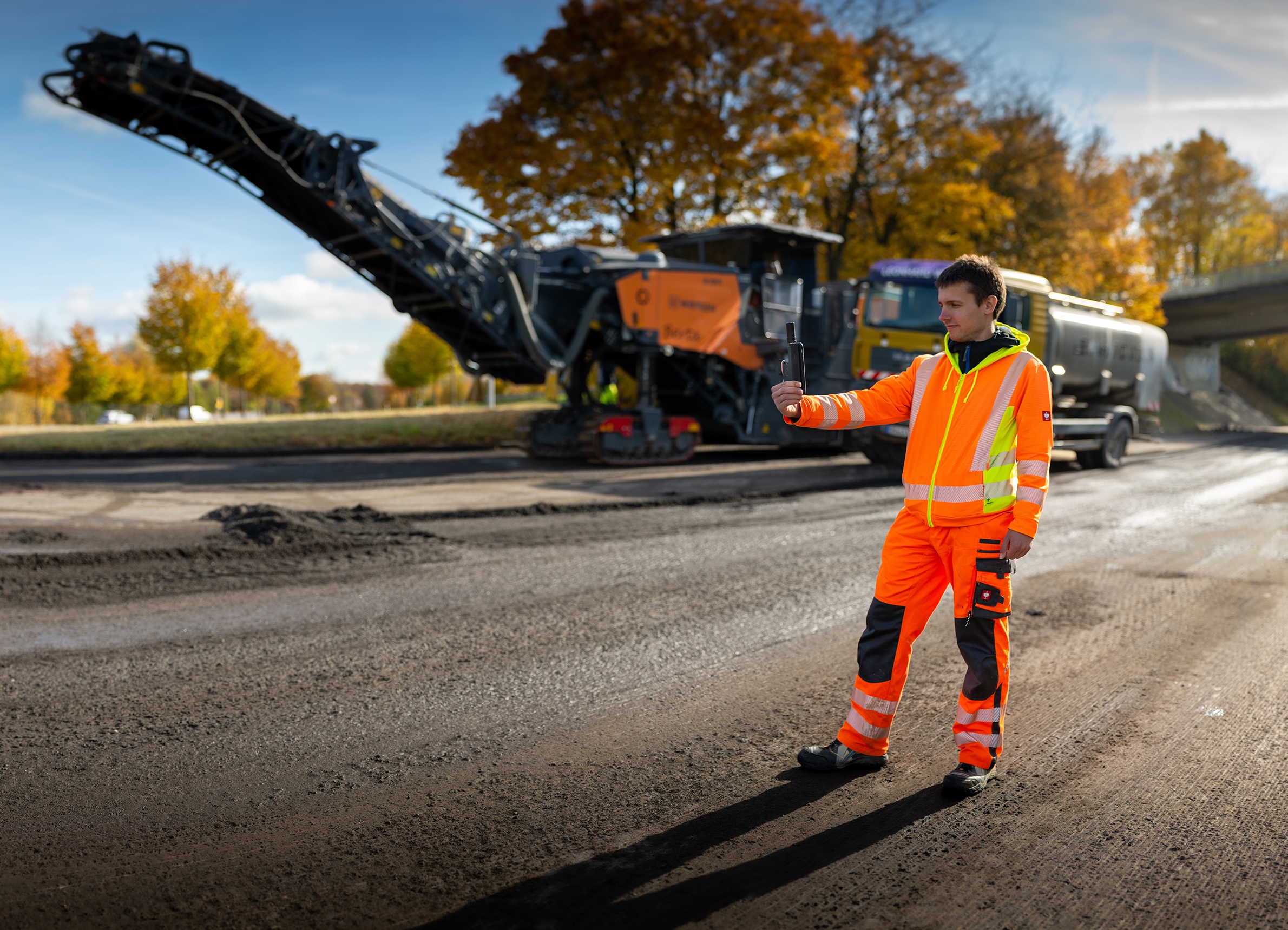 Das Bild zeigt die Baustelle einer Straßensanierung mit einem Bauarbeiter mit digitalem Gerät.