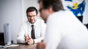 Bundesjustizminister Marco Buschmann hemdsärmelig im gespräch mit einer Person, die man nur unscharf und von hinten sieht.