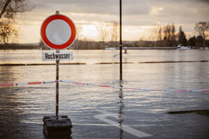Hochwasserwarnschild vor einer überfluteten Fläche