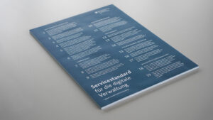 Printversion des Servicestandards liegt auf einer hellgrauen Tischfläche.