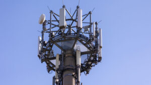 Mobilfunkmast aus der Untersicht aufgenommen, gegen blauen wolkenlosen Himmel.