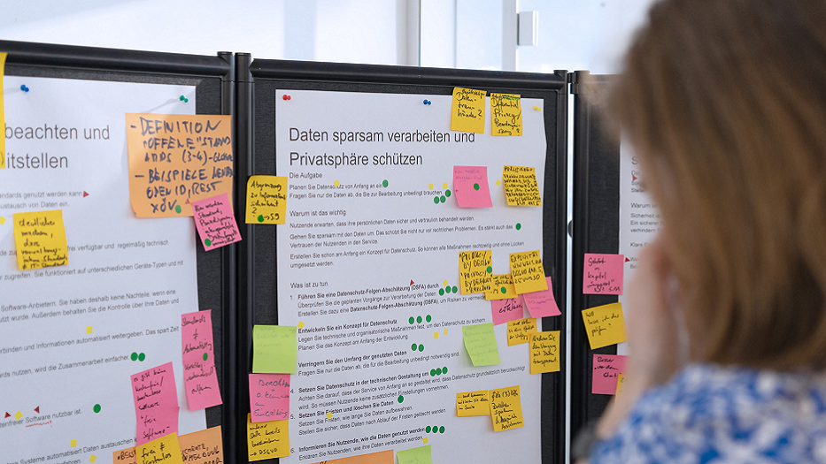 Blick auf Stellwände, die mit Stichpunkt-Listen und vielen bunten Post-Its beklebt sind.