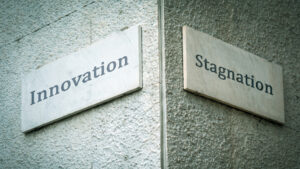 Hausecke mit zwei Straßenschildern, links "Innovation", rechts "Stagnation"