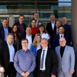 Gruppenfoto von rund einem Dutzend Personen auf der Außentreppe eines modernen Gebäudes.