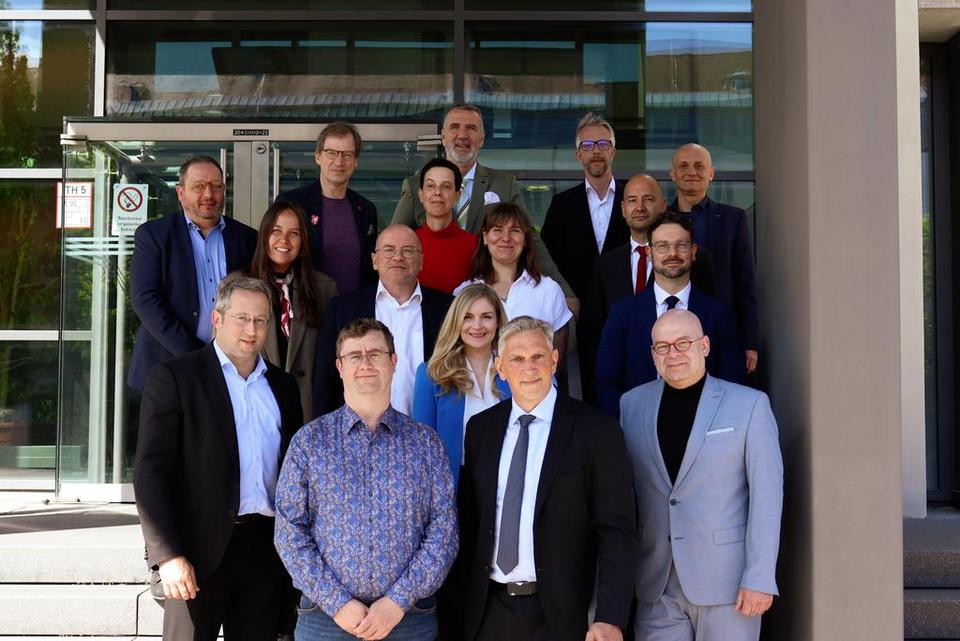 Gruppenfoto von rund einem Dutzend Personen auf der Außentreppe eines modernen Gebäudes.