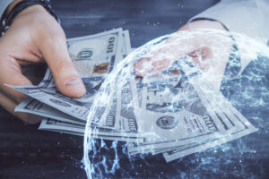 Doppelbelichtung von einem paar Hände, die Geld zählen, davor der Umriss einer Weltkugel.