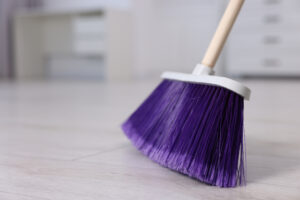 Nahaufnahme eines Besens, der einen mutmaßlichen Bürofußboden kehrt.