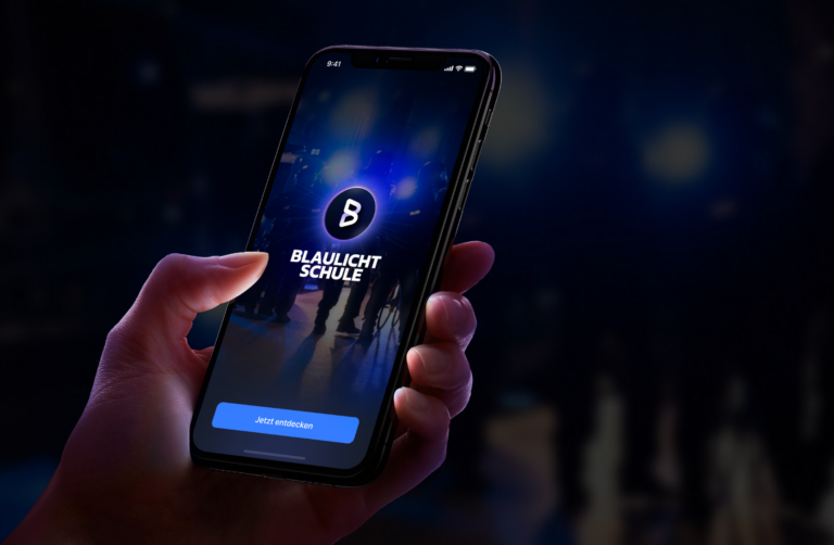 Hand hält ein Smartphone mit dem Logo der Blaulichtschule.