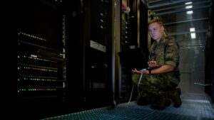 Ein Mann in Soldatenuniform kniet vor einem Serverrack.