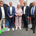 Personengruppe in Smart Casual-Kleidung hat sich zum Fototermin nebeneinander gestellt.