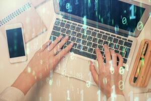 Frauenhände an einem Laptop mit einem Overlay aus Binärcode.