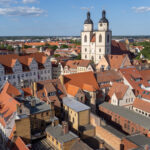 Luftaufnahme der Altstadt von Witenberg, im Bildzentrum ein heller Doppelkirchturm.