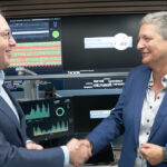 Innenminsietr Dobrindt und BSI-Chefin Plattner beim Handshake, im Hintergrund sieht man zahlreiche Monitore mit Grafiken und Statistiken sowie dem Logo "Nationales IT-Lagezentrum".