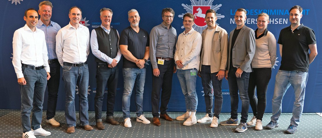 Das vorwiegend männliche Projektteam hat sich vor einer blauen Wand mit LKA-Niedersachsen-Logo zum Gruppenfoto aufgestellt.