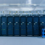 Modernes Rechenzentrum, ein IT-Techniker schiebt einen Wagen zwischen den Reihen der Server-Racks hindurch.