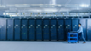 Modernes Rechenzentrum, ein IT-Techniker schiebt einen Wagen zwischen den Reihen der Server-Racks hindurch.