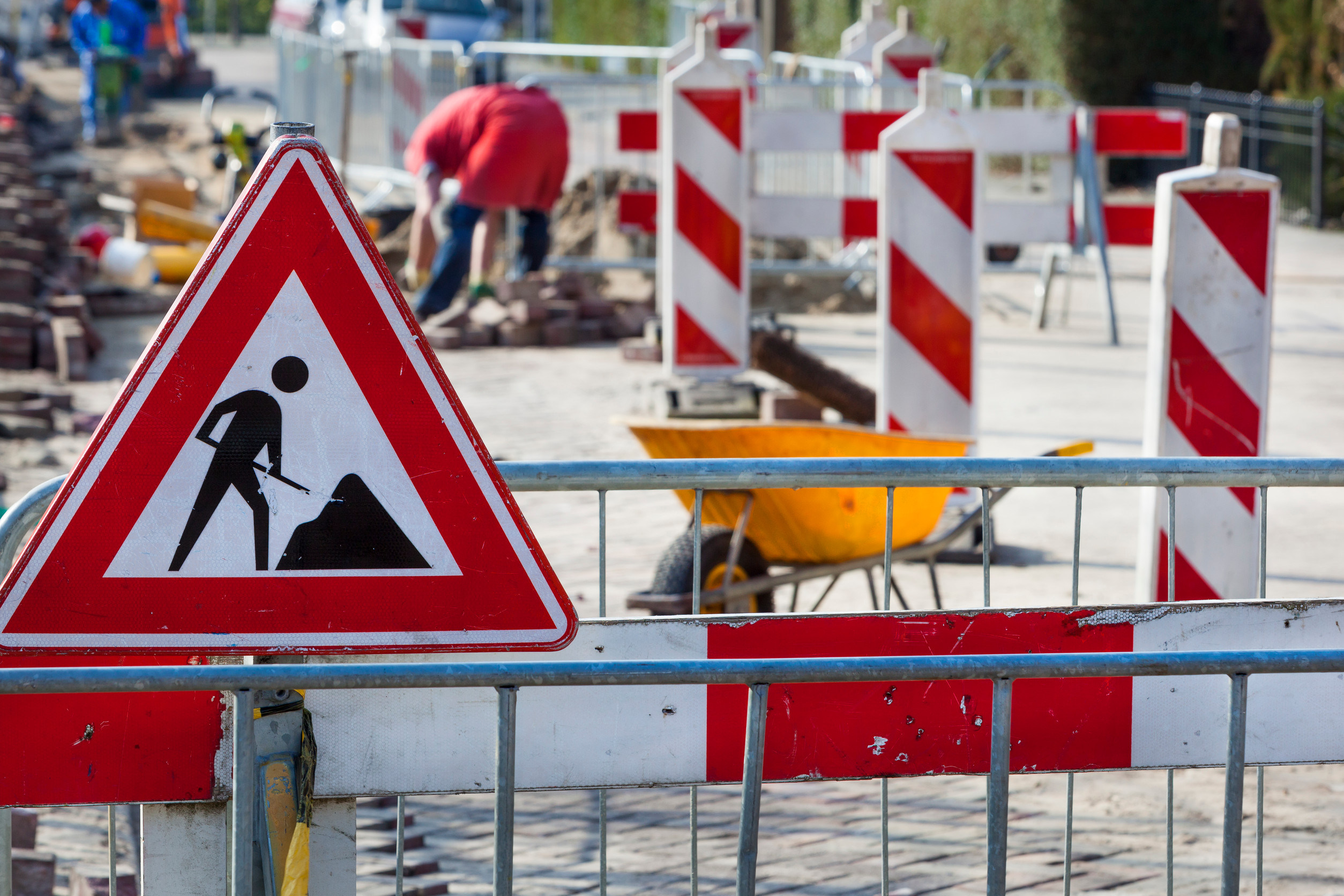 Straßenbaustelle mit Absperrbaken und einem Verkehrsschild, das Bauarbeiten signalisiert.