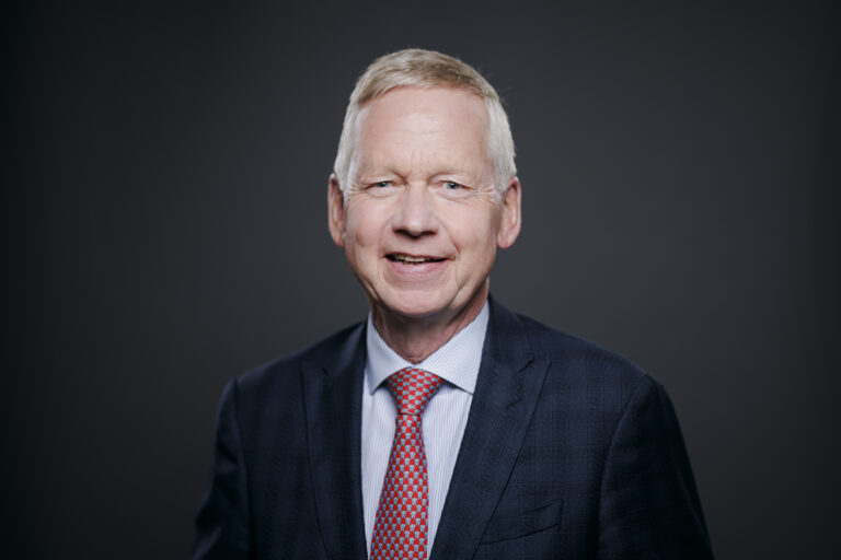 Porträt des NKR-Vorsitzenden Lutz Goebel vor dunklem Hintergrund.