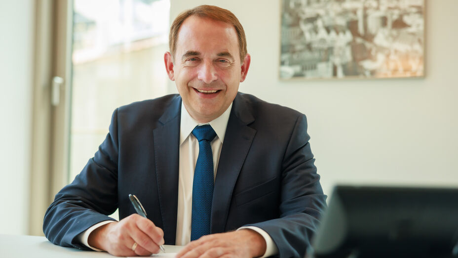 Porträt von Hessens Finanzminister Professor Dr. R. Alexander Lorz, anscheinend in seinem Büro etwas mit der Hand schreibend.