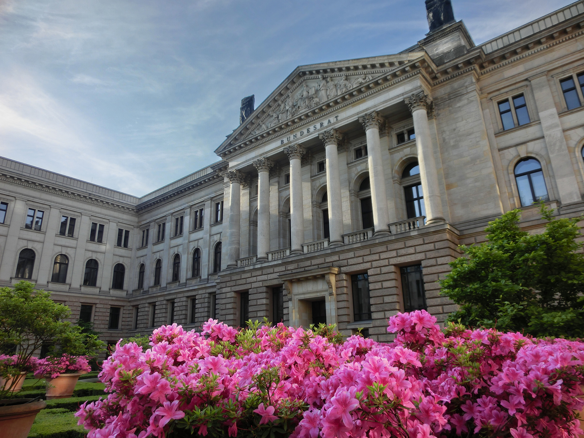 Außenansicht des klassizistischen Bundesratsgebäudes, im Vordergrund blühender Rhododendron.