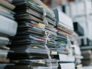 Nahaufnahme von Aktenstapeln und Papieren auf einer Tischplatte in einem Büro.