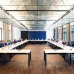 viele Personen sitzen an einem langen Tisch in U-Form