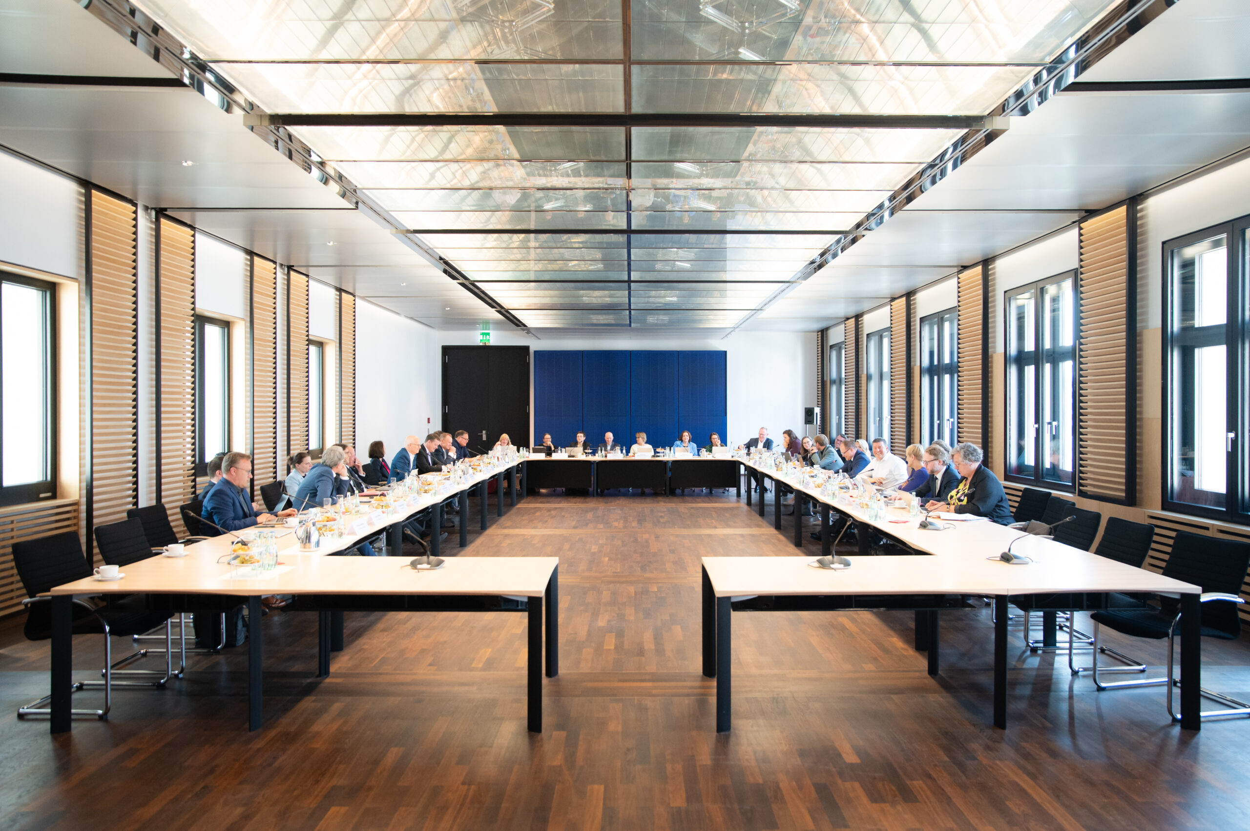 viele Personen sitzen an einem langen Tisch in U-Form