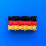 Plastikbausteine mit Noppen in den Deutschland-Farben, vor blauem Hintergrund