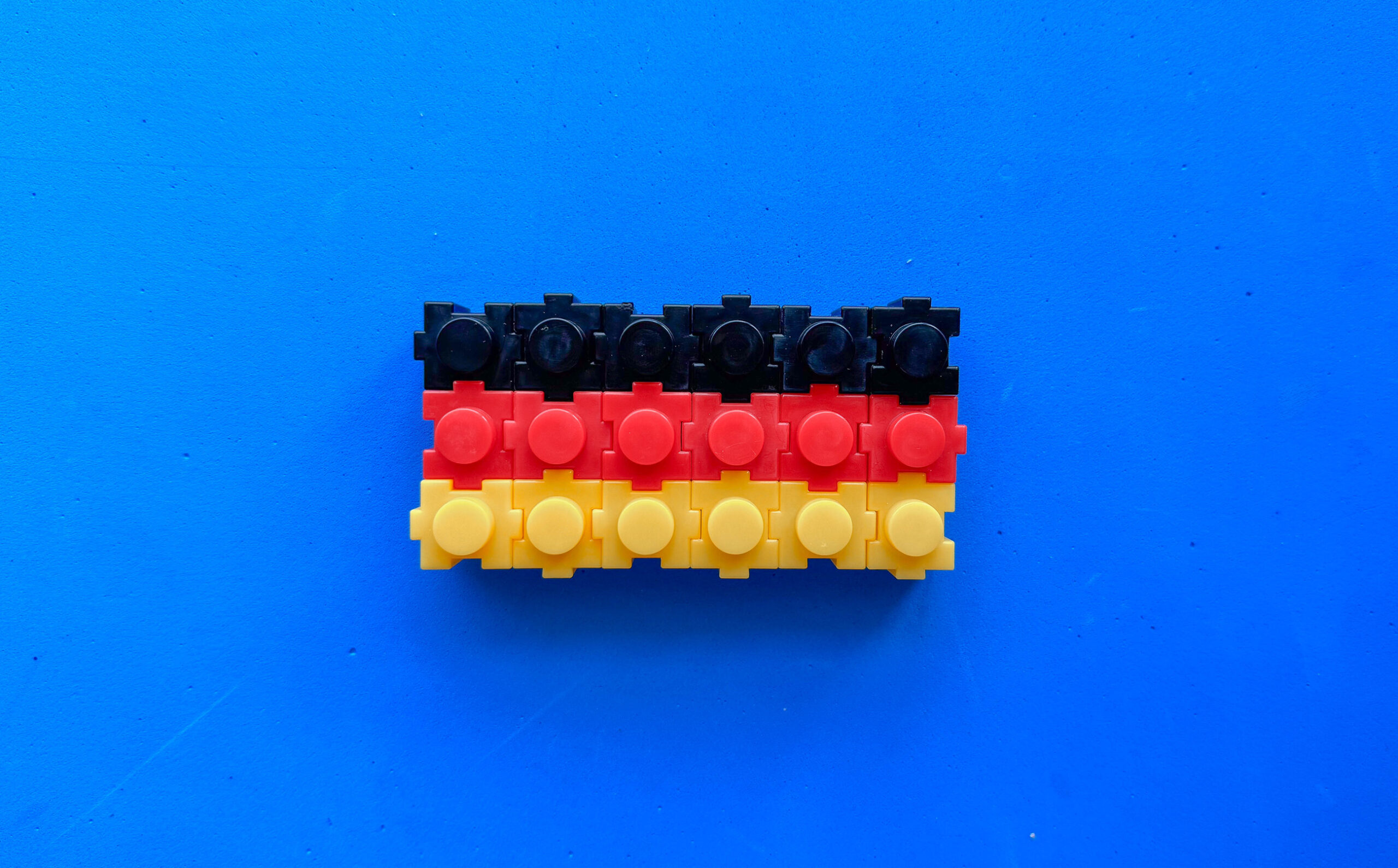 Plastikbausteine mit Noppen in den Deutschland-Farben, vor blauem Hintergrund