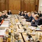 Blick über an einen langen Tisch, an dem Regierungsmitglieder sitzen.