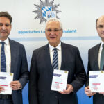 Die Minister stehen nebeneinander und halten je ein Exemplar des Berichts zur Cybersicherheit in Bayern 2025 in den Händen.