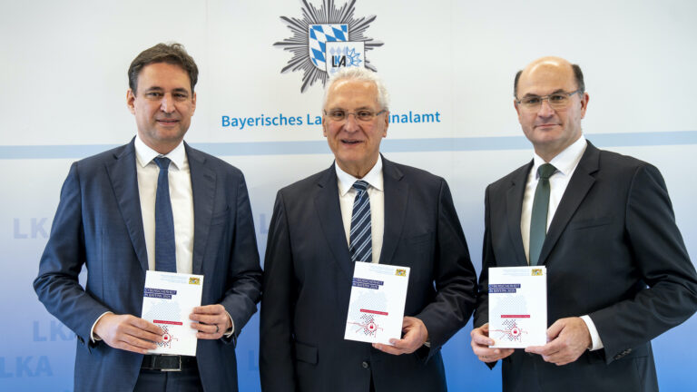 Die Minister stehen nebeneinander und halten je ein Exemplar des Berichts zur Cybersicherheit in Bayern 2025 in den Händen.