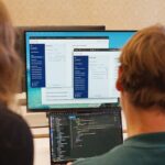 Man schaut über die Schultern von zwei Personen auf Monitore, auf denen offenbar BärGPT läuft.