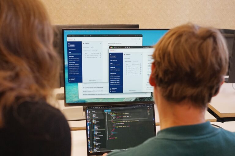 Man schaut über die Schultern von zwei Personen auf Monitore, auf denen offenbar BärGPT läuft.