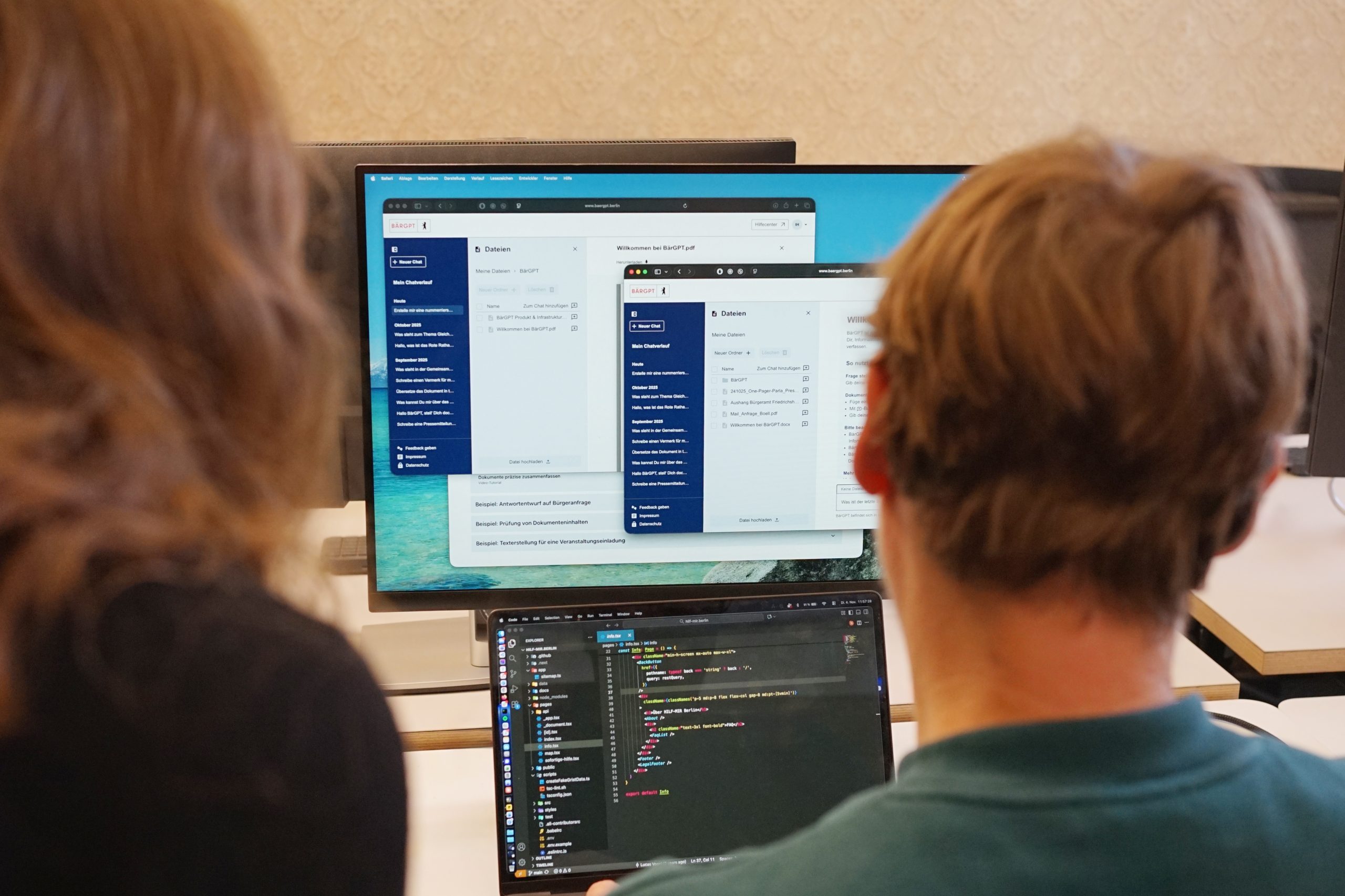 Man schaut über die Schultern von zwei Personen auf Monitore, auf denen offenbar BärGPT läuft.