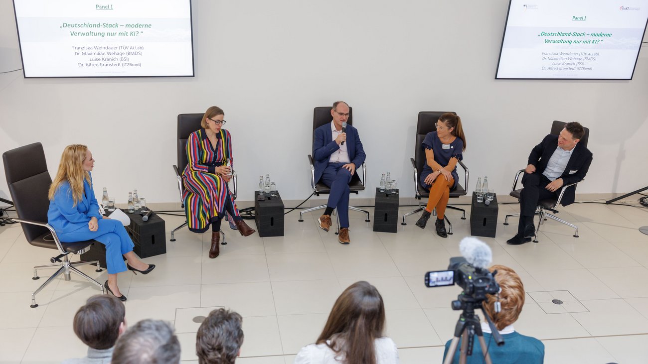 Aufsicht auf eine Personengruppe, die in einem hellen, nüchternen Raum in einem Stuhlkreis sitzt.