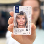 Unscharf dargestellte Frau hält Muster des PQC-Ausweises in die Kamera.