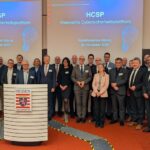 Foto einer größeren Personengruppe, die vor einer Projektion mit der Aufschrift "HCSP" posiert.