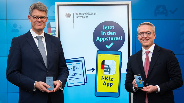 Bundesverkehrsminister Patrick Schnieder (li.) und Bundesdigitalminister Karsten Wildberger vor einer Werbewand für die neue App.