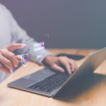 Laptop mit Schreibtischplatte, Händen und Oberkörper einer person. Overlay mit "Security"-Icons.