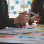 Mehrere Personen tüfteln per Brainstorming und Notizen an einer Strategie.