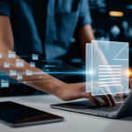 Eine Person arbeitet an einem Laptop mit digitalen Dokumenten und Ordnern.