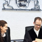 Richterin und Richter im Hintergrund das Landeswappen BW