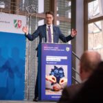 Hendrik Wüst in Segnungspose am Rednerpult.